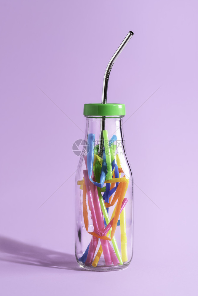 减少塑料污染概念将可重复使用的金属稻草放在装满彩色塑料的玻璃瓶中放在紫色纸上生态友好的饮用稻草上图片