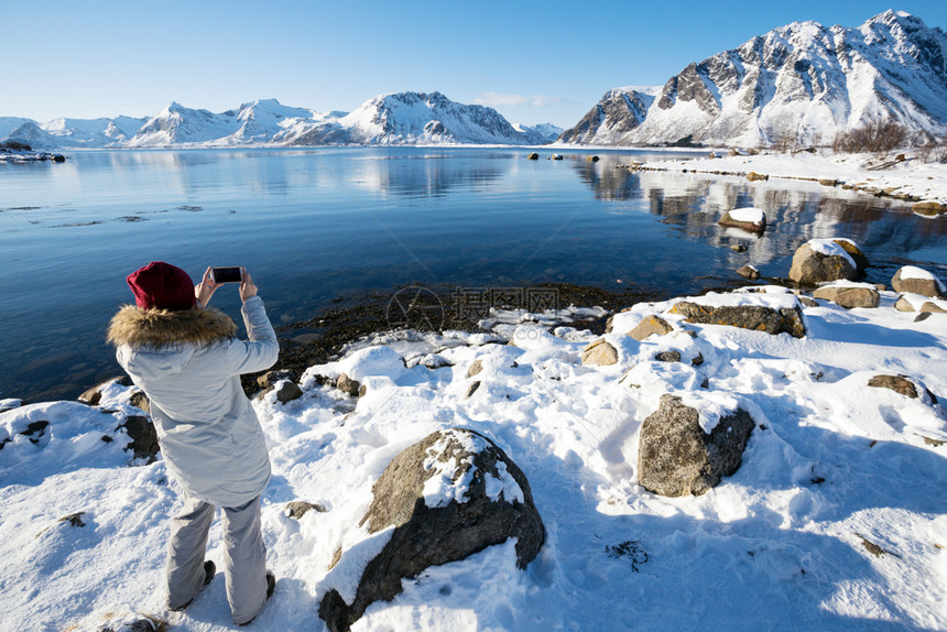 女孩环绕岛旅行用照相机拍美丽的挪威风景图片