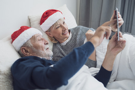 红帽家庭口语每天早上在卧室的圣诞节日使用平板退休爱家庭生活方式概念图片
