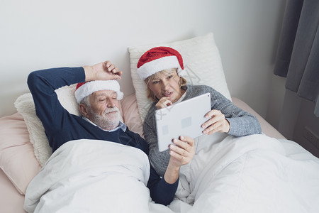 红帽家庭口语每天早上在卧室的圣诞节日使用平板退休爱家庭生活方式概念图片
