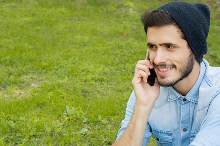 英俊的年轻人在公园里户外讲电话的肖像图片