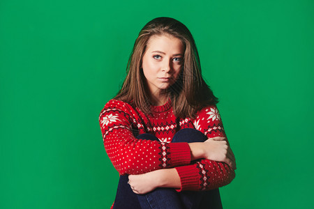 穿着圣诞节毛衣的年轻女绿色背景图片