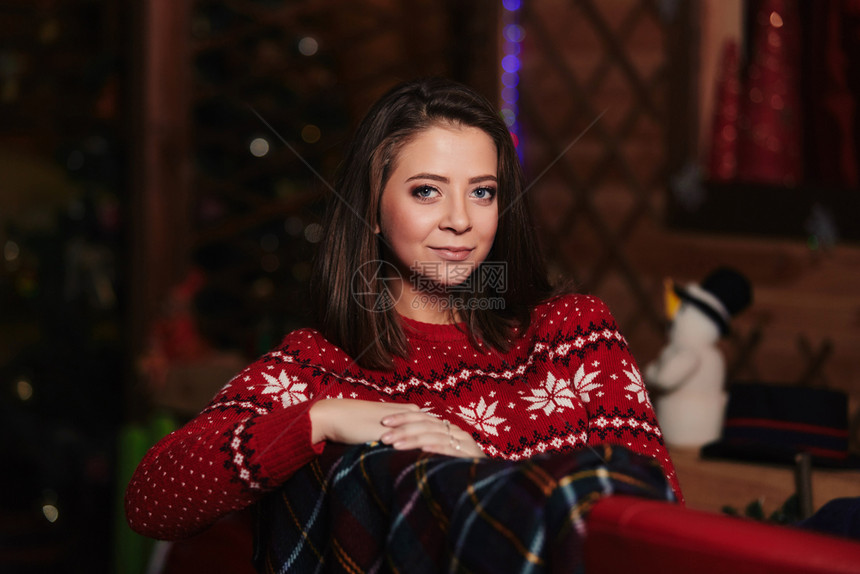 穿着红色圣诞节毛衣的年轻美女肖像后面的圣诞节背景假日概念图片