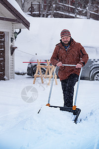 冬天在院子里铲雪的中年男性背景图片