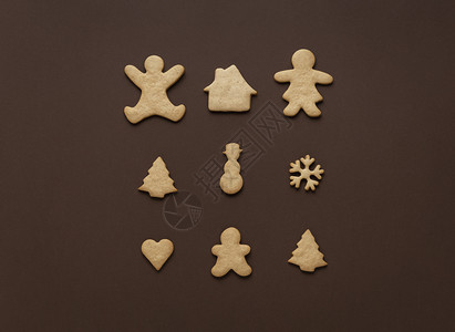以棕色背景的xmas树雪人和家庭为形状的姜饼干图片