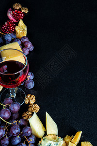 以黑背景角落形式安排红葡萄酒和零食带有复制空间图片