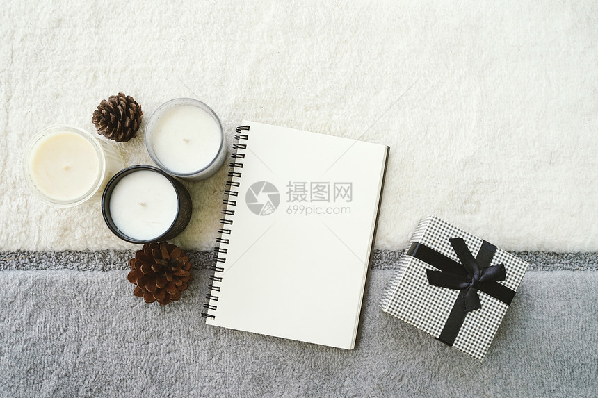 以空笔记本画员在编织背景和蜡烛上用礼物盒感恩节和假日概念图片
