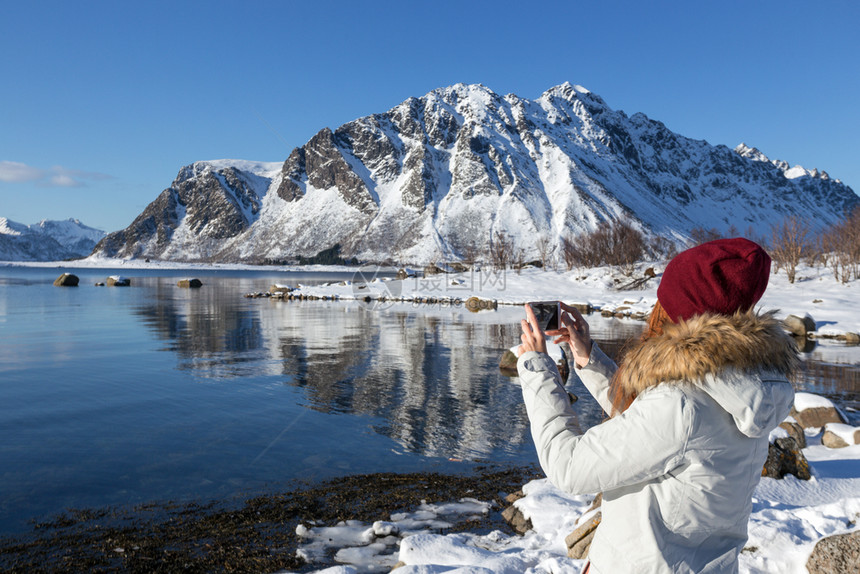 女孩环绕岛旅行用照相机拍美丽的挪威风景图片