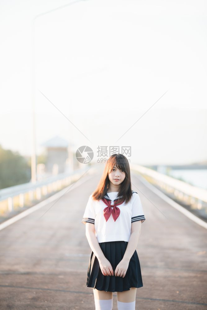 带着步行道和河边微笑的日本女学生制服图片