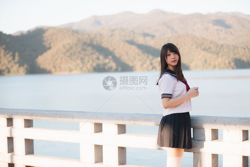 带着步行道和河边微笑的日本女学生制服图片
