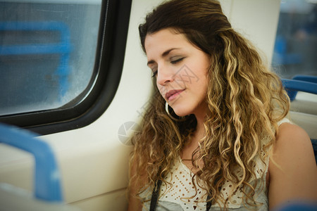 城市的年轻女子睡在火车上坐窗户旁边的火车上现代人的城市生活方式图片