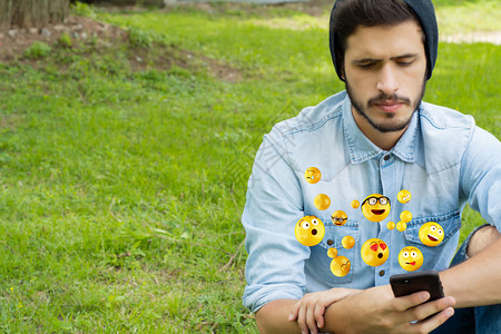 年轻拉丁人使用智能手机发送emojis社会概念图片