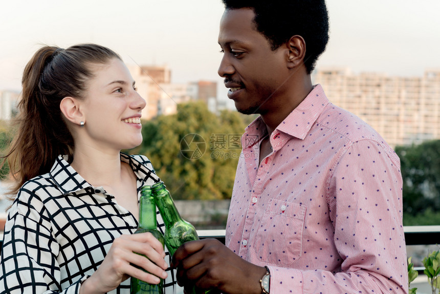 一群年轻的多民族朋友在户外屋顶庆祝喝瓶酒玩得开心图片