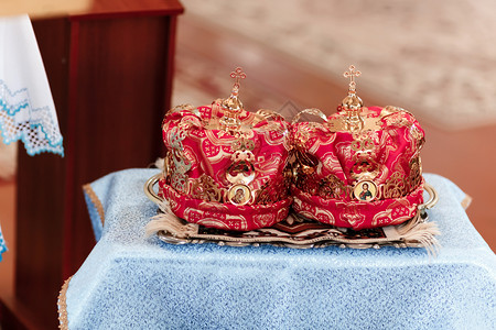 红色皇冠金冠和放在一个教堂桌上准备举行婚礼仪式皇冠在教堂里准备举行婚礼仪式金冠和在教堂桌子上准备举行婚礼仪式背景