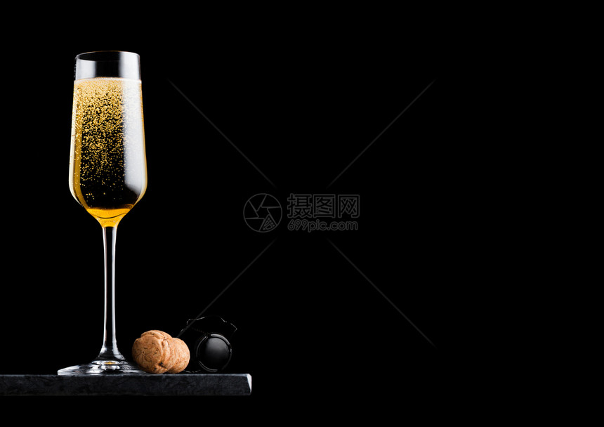 优雅的黄色香槟杯子黑大理石板上背景的软木和铁笼图片