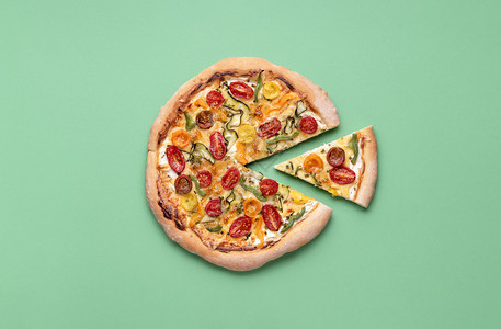 绿背景的素食披萨初和一小片的春披萨意大利餐樱桃番茄披萨图片