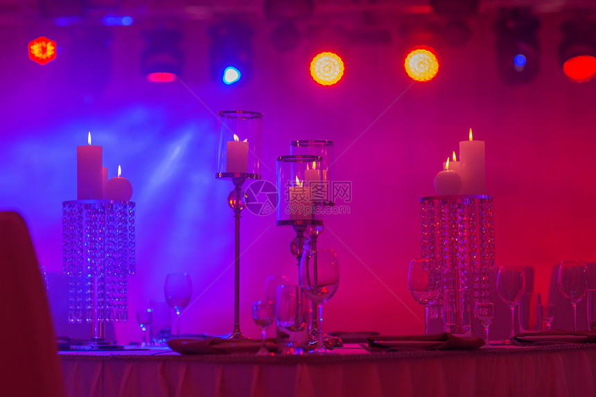 宴会厅的桌上装饰着彩色灯光的蜡烛和银台图片