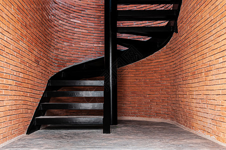 黑色金属螺旋楼梯有红砖墙和锈水泥地板图片