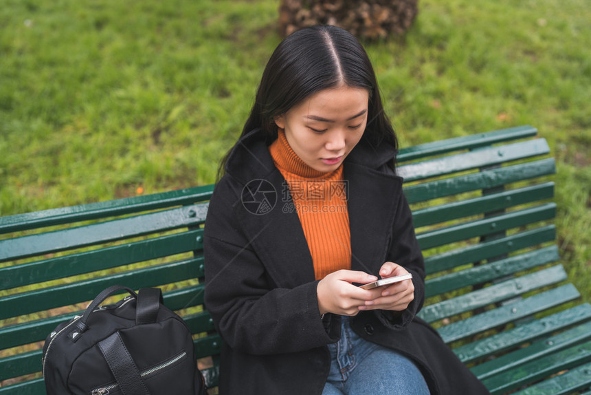 女人坐在公园长椅上使用手机图片