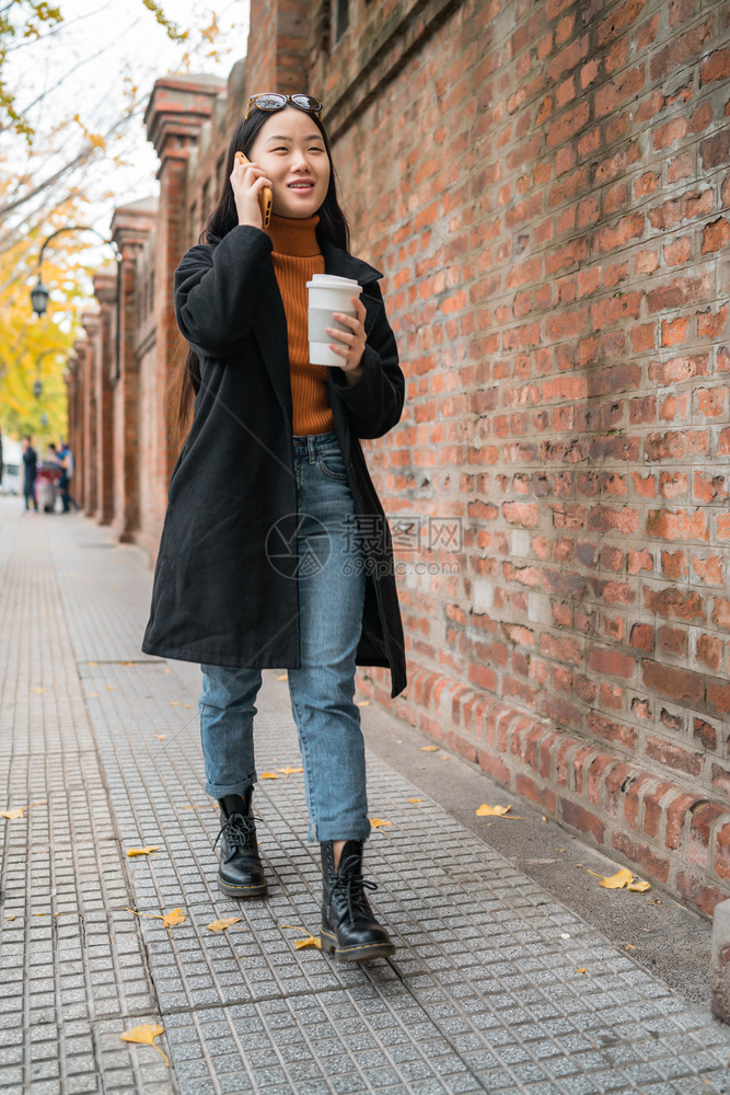 年轻女在街上喝咖啡时电话上聊天的肖像图片