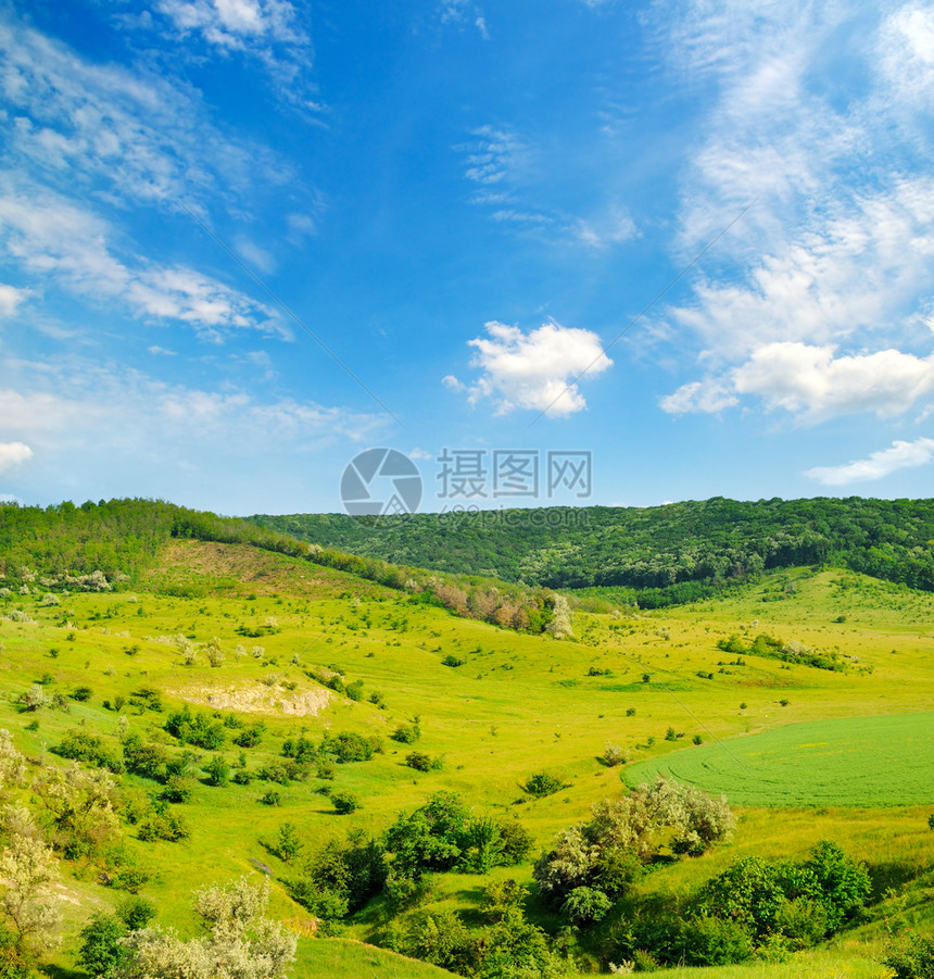 有树木和灌的山丘绿地蓝天上有美丽的乌云图片