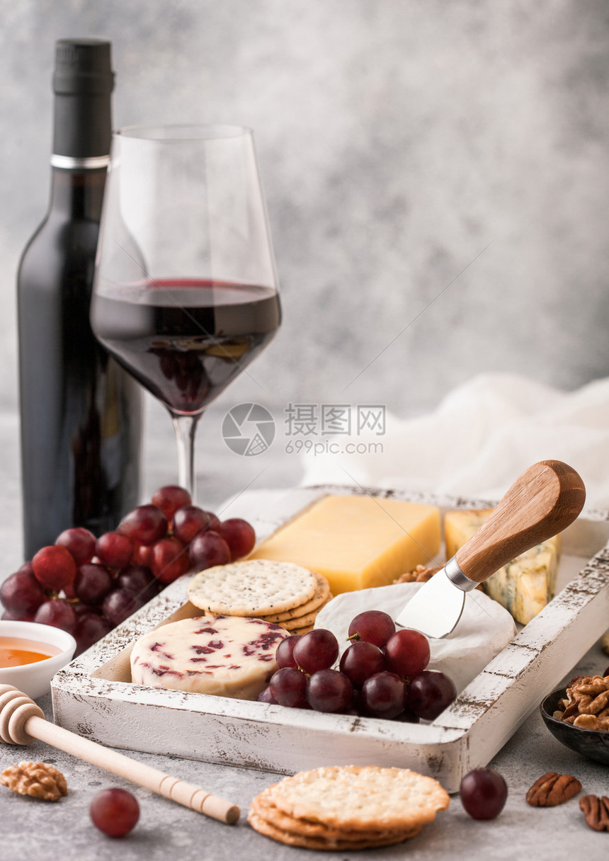 玻璃红葡萄酒和一瓶在木箱中选取各种奶酪在浅底的葡萄上选取各种奶酪图片