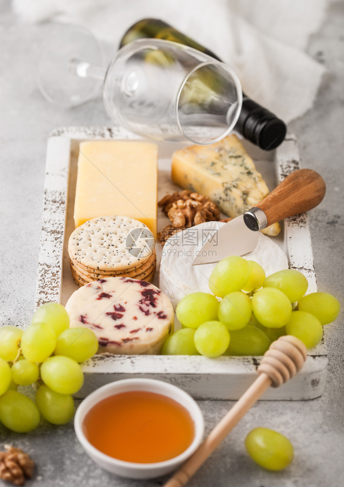 白葡萄酒和在木箱中挑选各种奶酪和木底葡萄图片