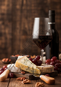 玻璃红葡萄酒和在板上挑选各种奶酪和木制桌底的葡萄高清图片