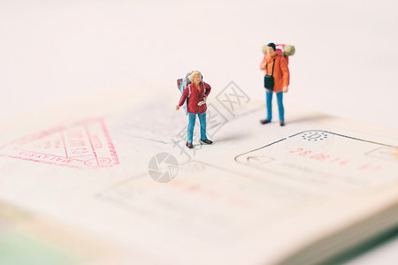 背起行走和在护照页上站立并印有移民邮票旅行和休假概念的微型人数图片