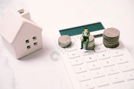 小模型的素材拥有房屋金融和地产概念的计算器上硬币堆积如山背景