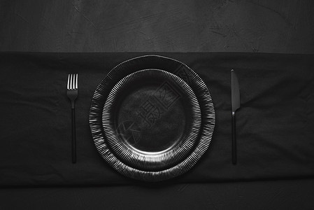 黑桌上有两个空盘子和餐具以上是所有黑桌餐具晚设置现代具空盘桌安排图片