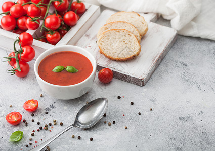 白碗盘的奶油番茄汤匙在浅底背景上还有一盒生番茄和面包文本空间背景图片