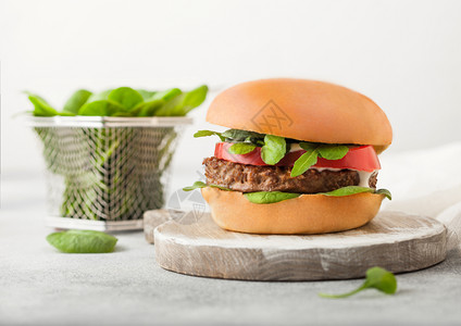 健康素食免费肉汉堡在圆形切肉板上加蔬菜和菠背景浅图片