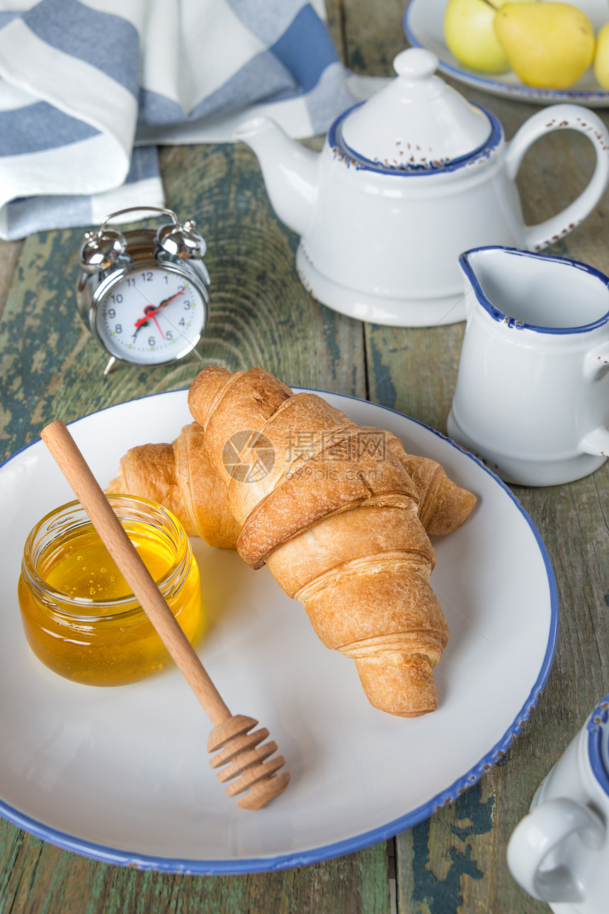 早餐包括一杯茶和带蜂蜜的羊角面包图片