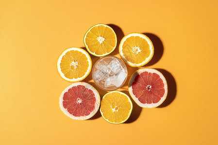 新鲜柑橘水果和中间的冰杯橙色背景阳光下在切橙子和葡萄汁的外观健康饮品图片