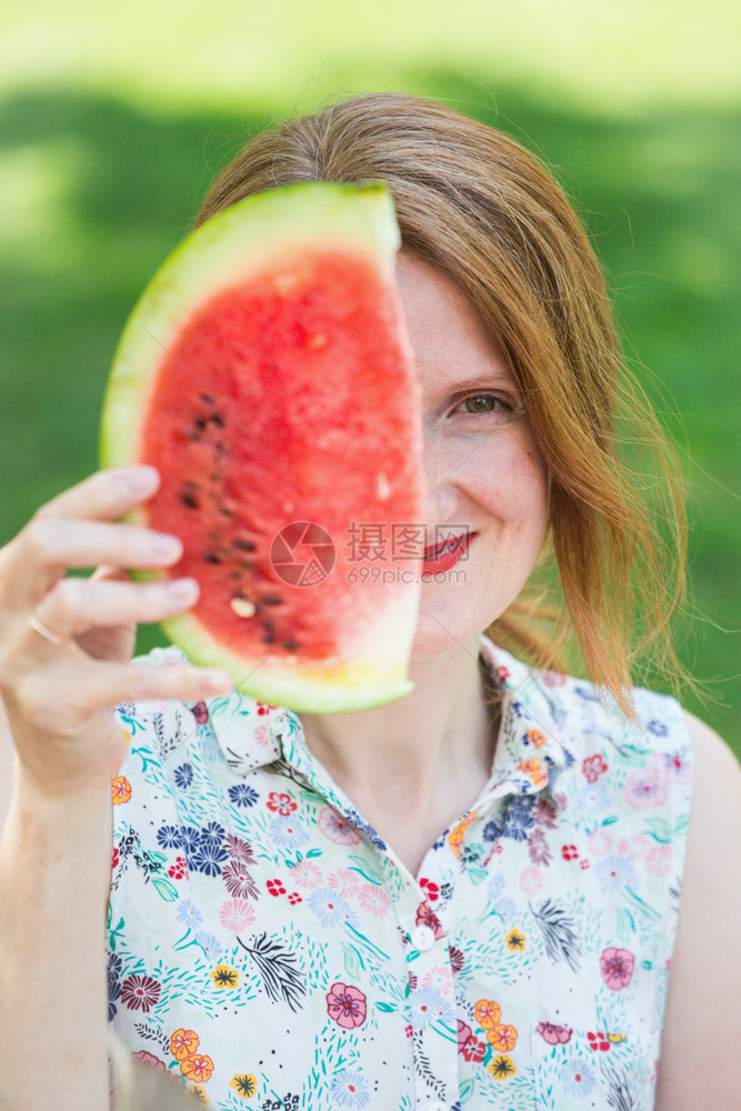 快乐的夏天女孩用一块西瓜覆盖她半张脸图片