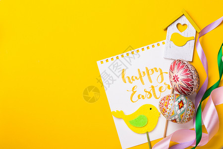 黄色手绘丝带手工制作带小鸟图案的贺卡和彩色鸡蛋背景