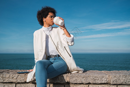 年轻拉丁女人在喝咖啡时边听音乐用耳机听声背景音乐生活方式图片