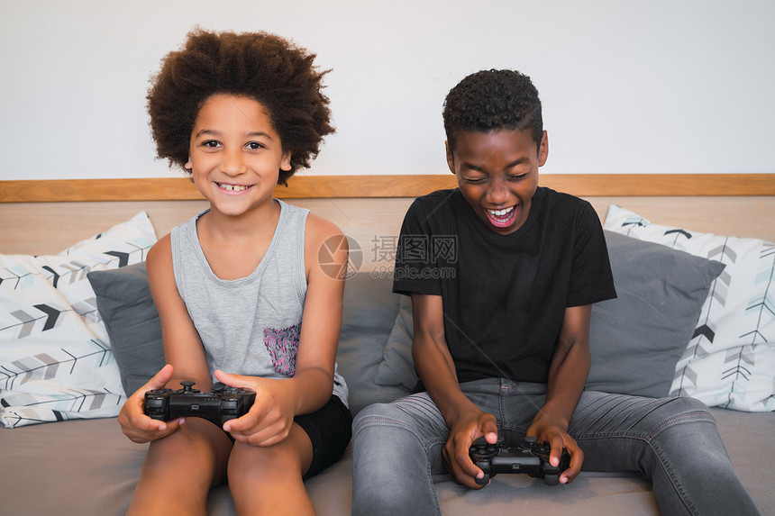 两个美国兄弟在家里玩电子游戏的肖像生活方式和技术概念图片