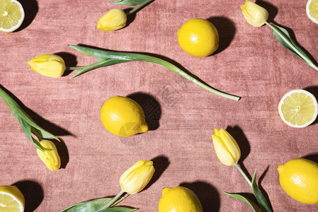 百变花样鲜柠檬和黄郁金香在阳光下的变装桌布上黄果和花样背景柑橘水果和郁金香的图象背景