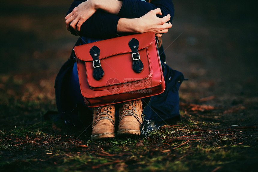 穿着棕色鞋子和温暖大衣的时装年轻女孩坐在公园里图片
