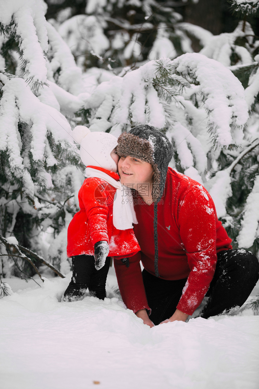 快乐的小女孩穿着红色大衣父亲在冬季森林里玩雪女孩和爸一起玩在冬天森林里玩雪图片