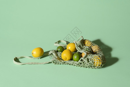 全钢无网绿色背景的可再用织布购物袋中的柠檬和带柑橘水果的生态友好型网包夏季水果食品购物概念背景