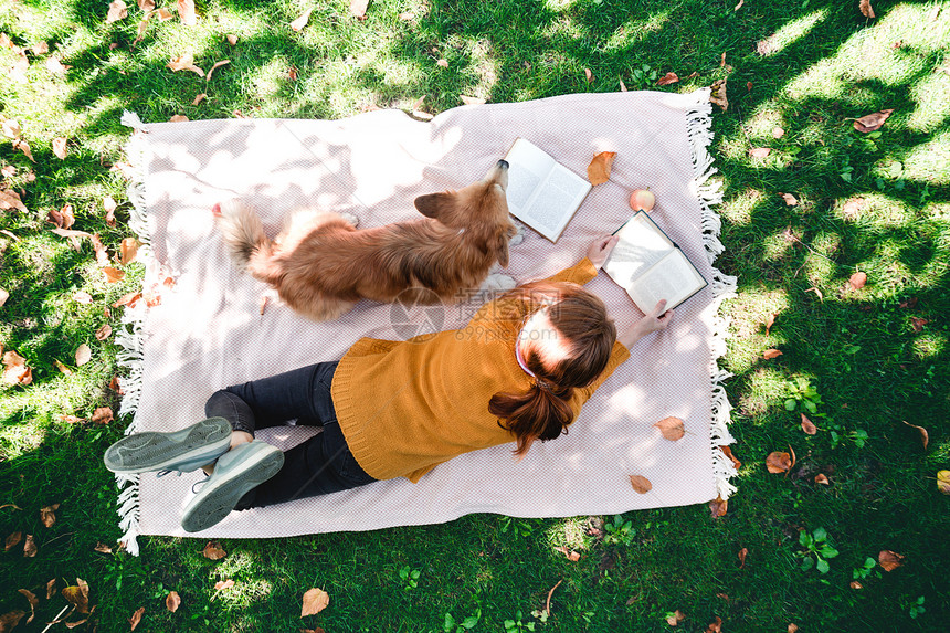 女孩和狗躺在草坪上看书图片