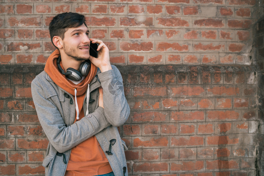 年轻拉丁男子在街上户外电话交谈的肖像城市和通信概念图片