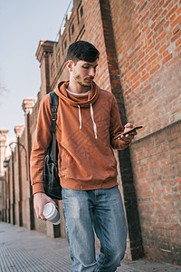 年轻帅哥用手机在街上户外拍摄的肖像图片