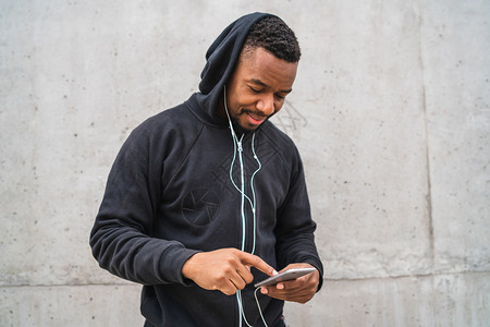 一名运动员在脱离训练时使用手机灰色背景运动与健康生活方式图片