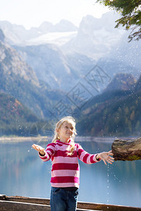 女孩从秋山的木制水沟里喝高清图片