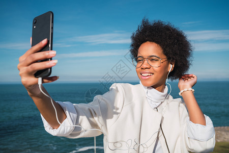 拉丁女人在海边用手机自拍图片