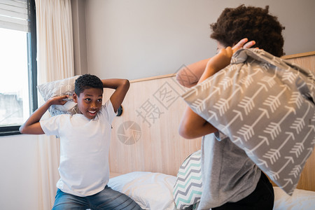两个兄弟在家里打架玩枕头的肖像生活方式的概念图片